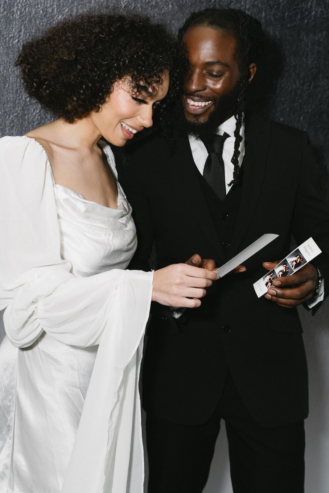 Bride and groom smiling at their photo booth strip