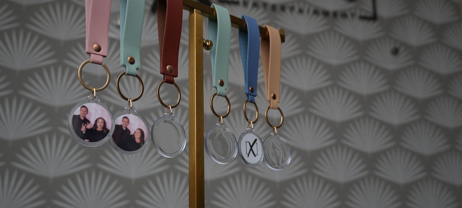 Custom leather keychains with gold hardware and photo inserts hanging on a display