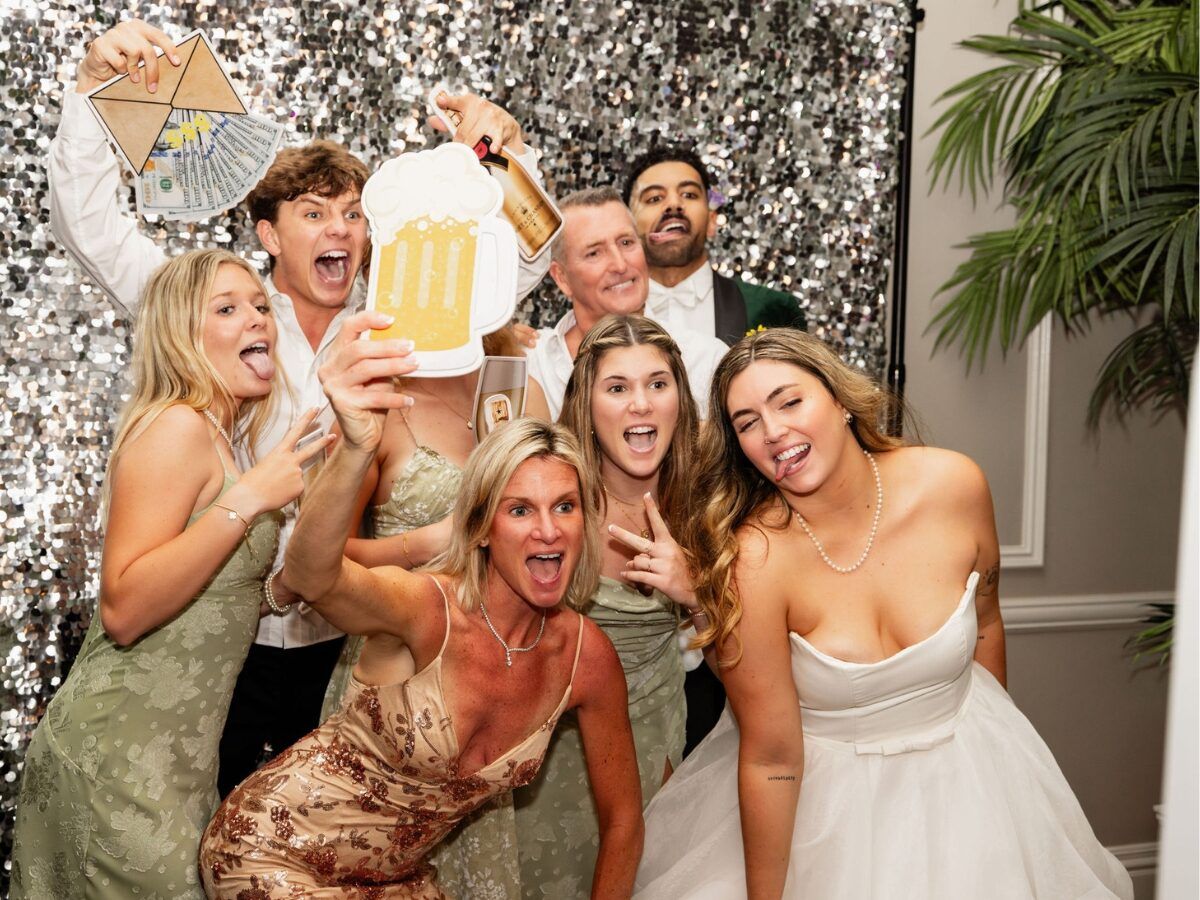 Party guests laughing with props in front of a sequin backdrop